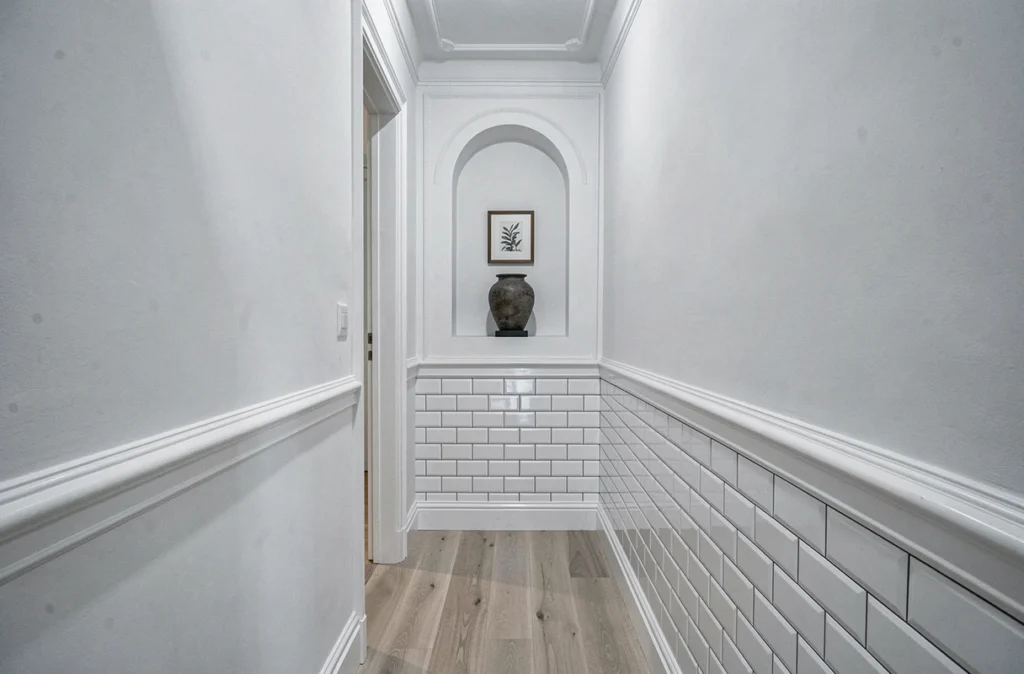 Couloir haussmannien étroit avec niche décorative, carrelage métro et peinture blanche pour maximiser la sensation d'espace